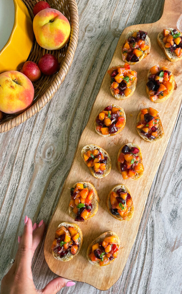 Peach and cherry crostini make the perfect summertime appetizer! Delicious and so simple using what's in season for summer: peaches and dark cherries combined with fresh basil, parmesan, olive oil and honey all on a slice of toasted baguette. What could be better? | Get the recipe on kirstenturk.com