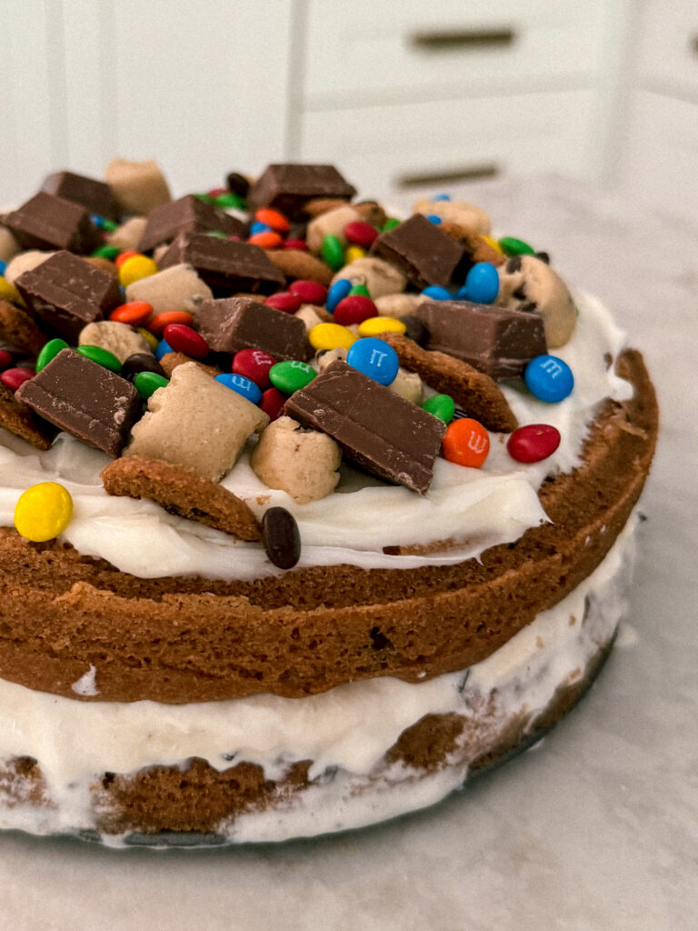 This Chocolate Chip Cookie Dough Ice Cream Cake is so good! Think of a giant ice cream cookie sandwich, soft and chewy cookie with cookie dough ice cream in-between. Topped with candy and more cookie dough. It's the perfect birthday cake for cookie dough lovers! Get the details on kirstenturk.com